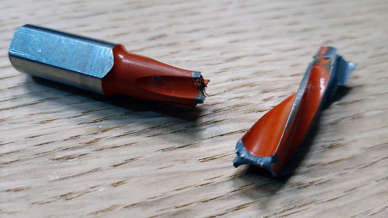 A broken drill bit on a wood background