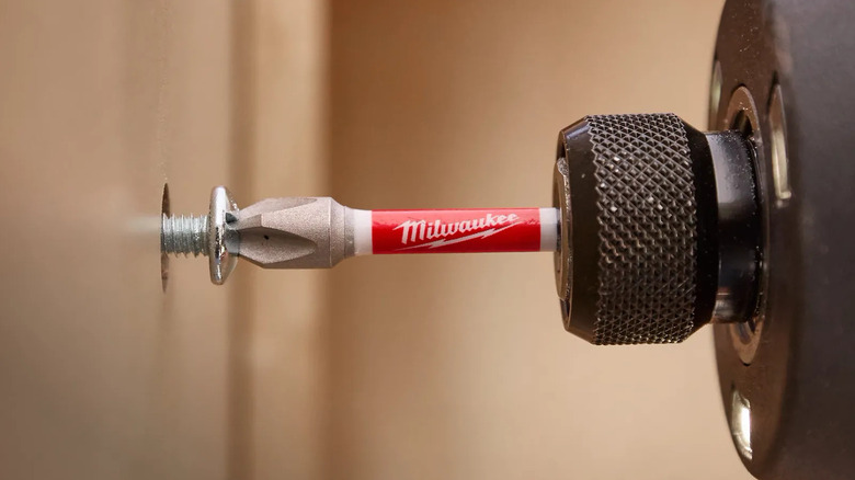 Close up of Milwaukee impact driver bit driving a screw into a hole