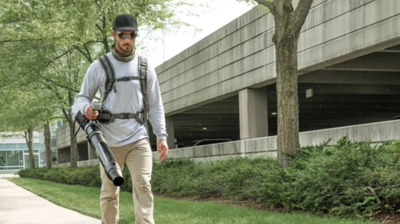 A man using a backpack leaf blower from Ego Power to clear a sidewalk of debris
