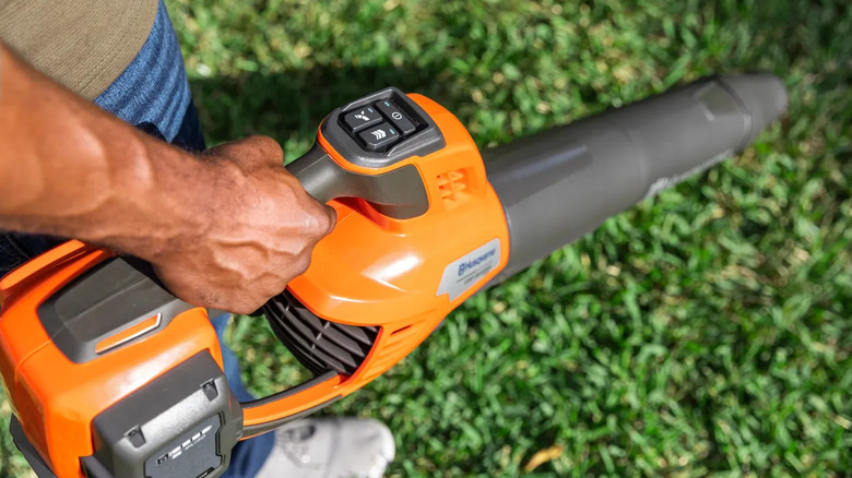 A man holding an orange Husqvarna leaf blower