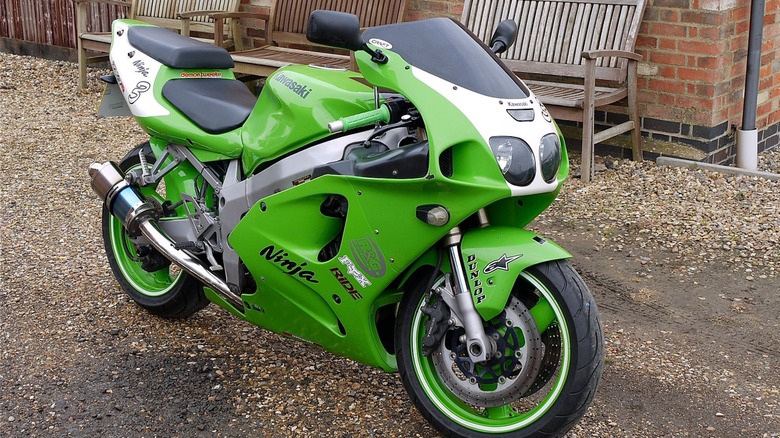 A green Kawasaki Ninja ZX-7R parked near park benches