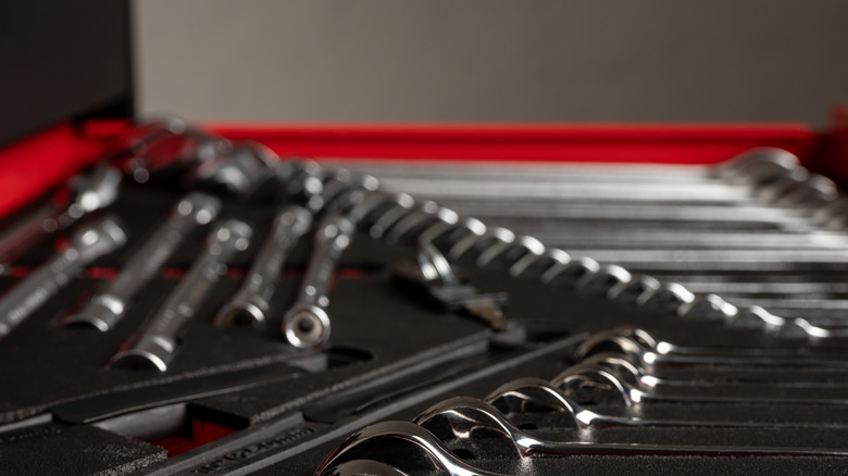 A closeup of various wrenches and other tools in an open drawer.