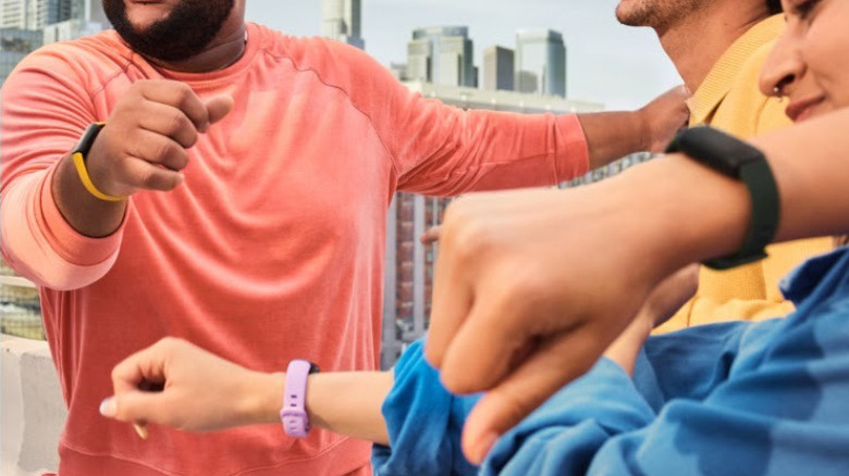 Three people wearing Fitbits in their workout clothes