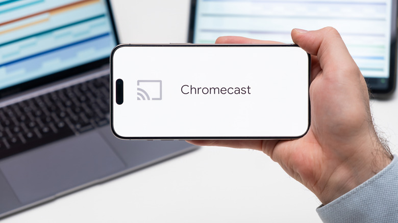 A hand holding a phone with the Chromecast logo
