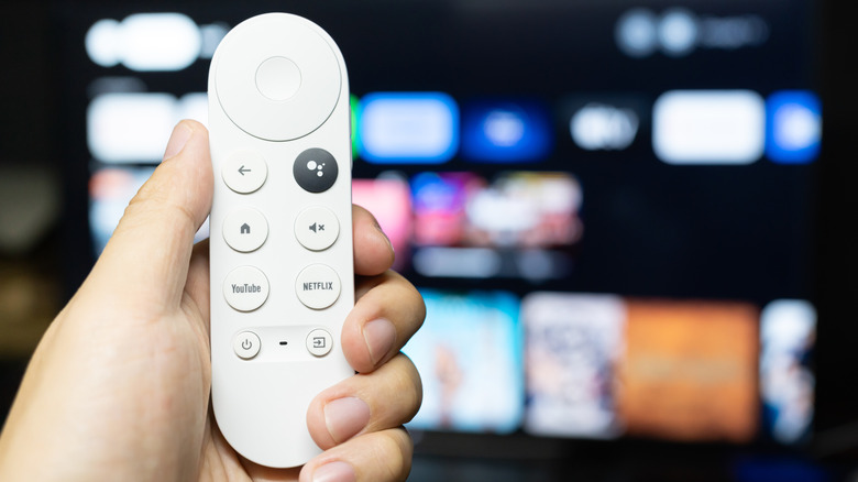 Chromecast remote held in hand in front of TV