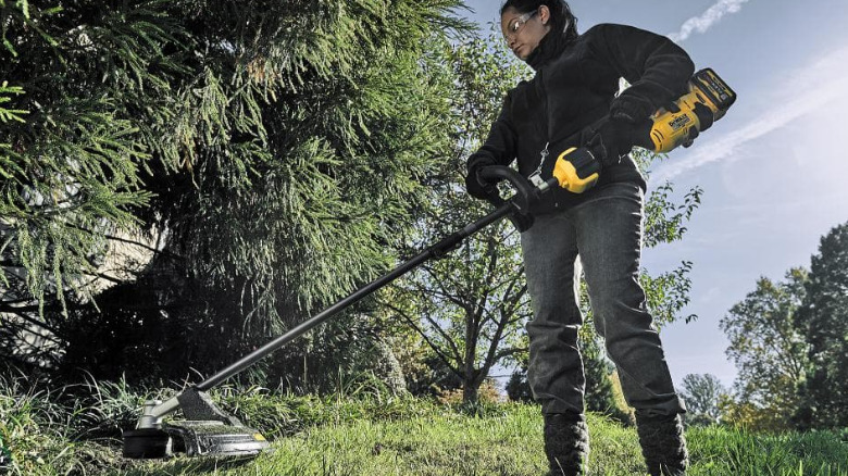 A person using the 60V Max String Trimmer on a grass field.