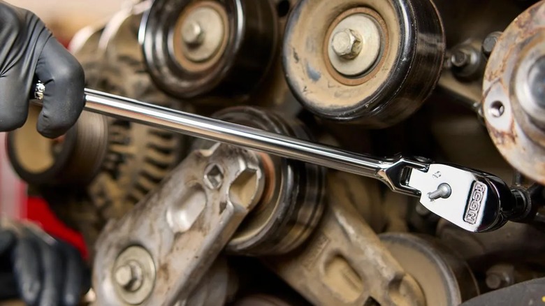 Close up of a person using an Icon ratchet on a car engine.