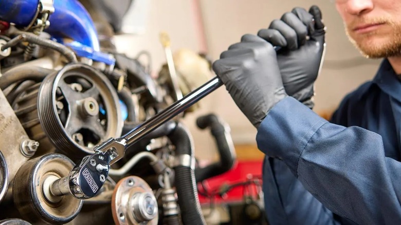 Close-up of a person using an Icon ratchet on a car engine.