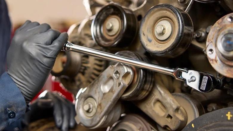 Close-up of a person using an Icon ratchet on a vehicle engine.