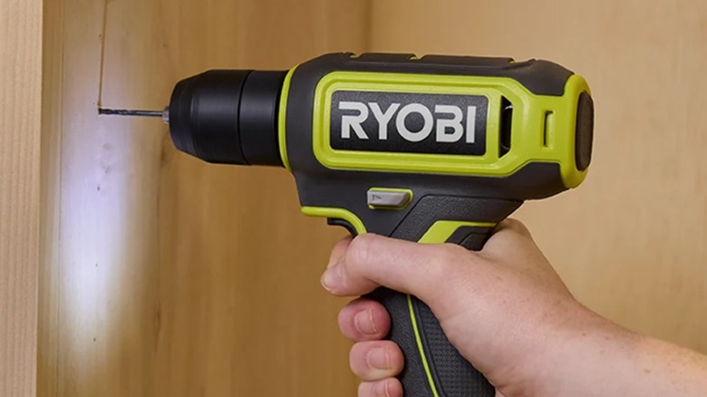 A person using a Ryobi drill on wood.