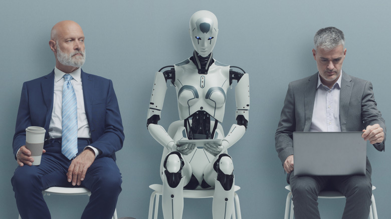 Two male humans in suits sitting on chairs with a robot sitting between them