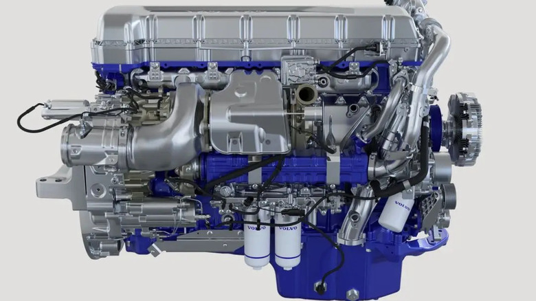 A silver and blue Volvo D13 diesel semi truck engine shown here against a gray studio backdrop.