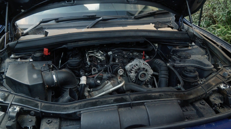 A blue BMW X1 from the e84 generation, with the hood propped open, showing the n47 diesel four-cylinder engine.﻿