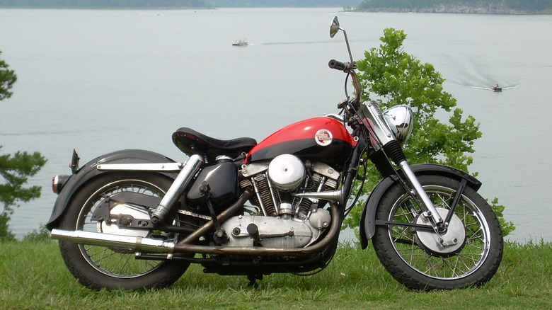 A black and red 1957 Harley-Davidson XL Sportster parked beside a lake