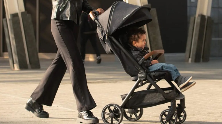 child in Nuna TRVL LX lightweight stroller pushed by woman