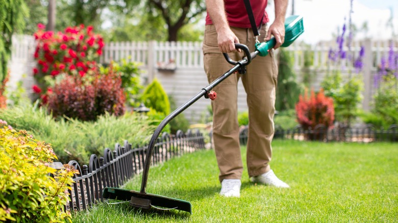 Person trimming weeds with electric weed eater.