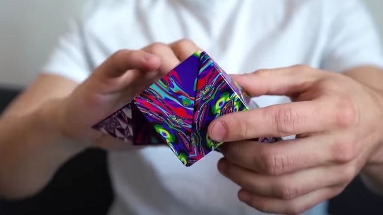 A person manipulating a colorful variety of the Shashibo Shape Shifting Box