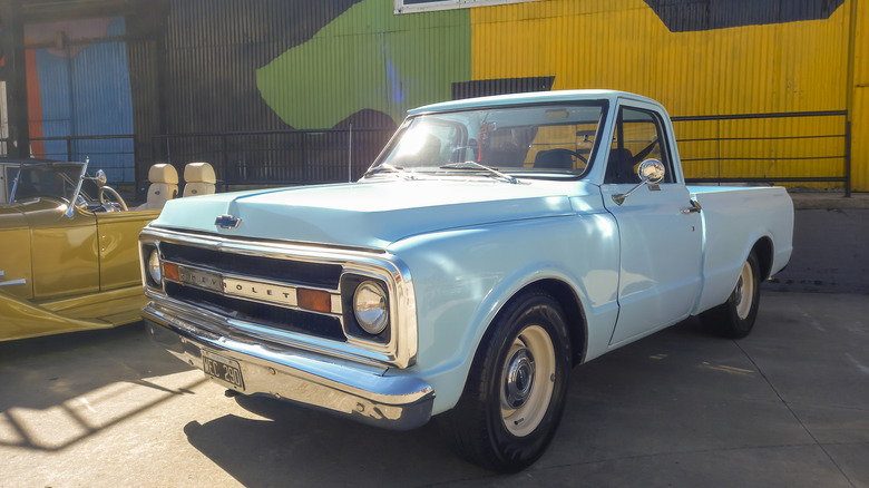 A light blue 1969 Chevrolet C10 parked in front of a brightly-painted wall