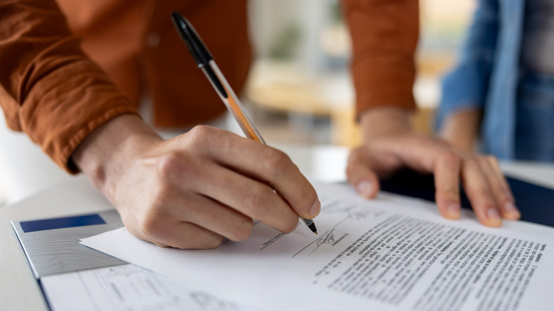 A person signing a contract on a table