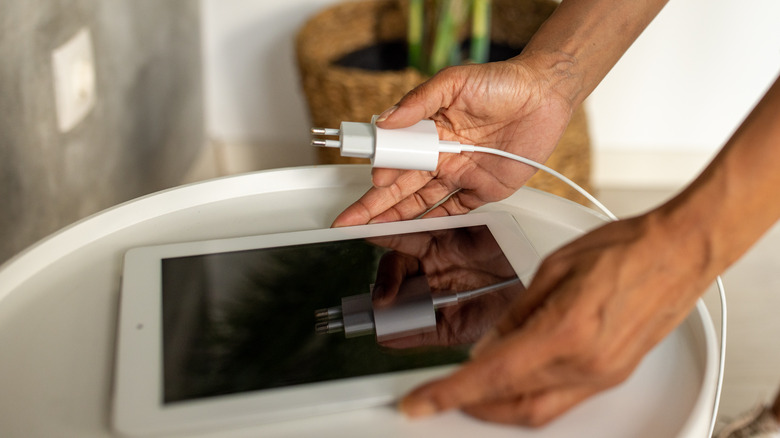 hand holding iPad and charger