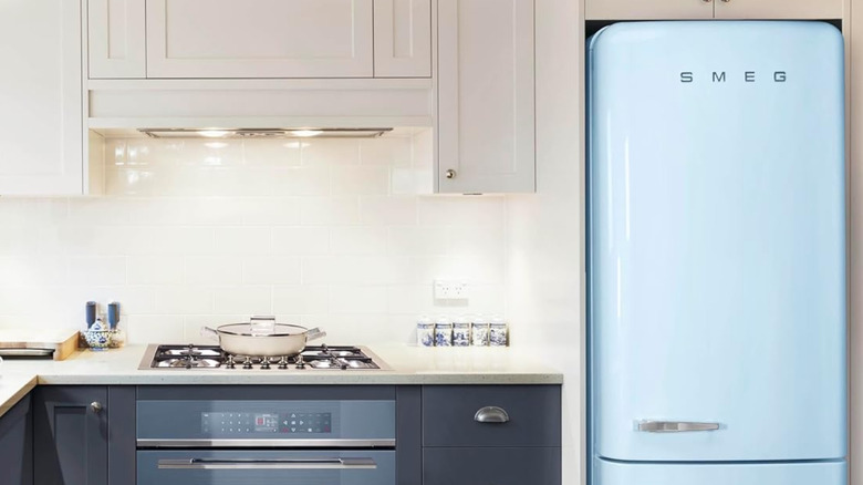 A light blue Smeg fridge next to a gas cooktop.