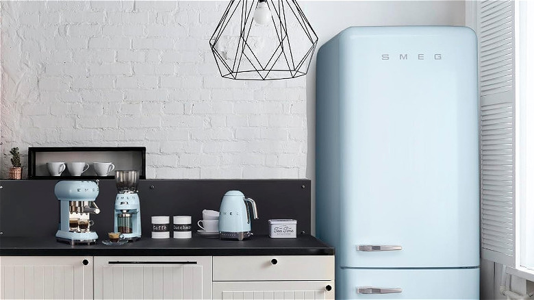 A light blue Smeg fridge in a kitchen, next to other Smeg appliances.