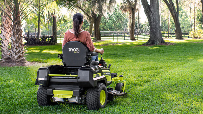 A woman riding a Ryobi brand riding mower