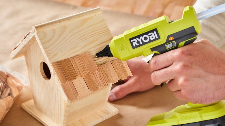 person gluing a birdhouse