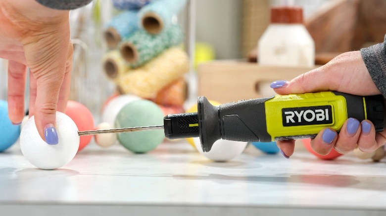 person making a hole in a foam ball