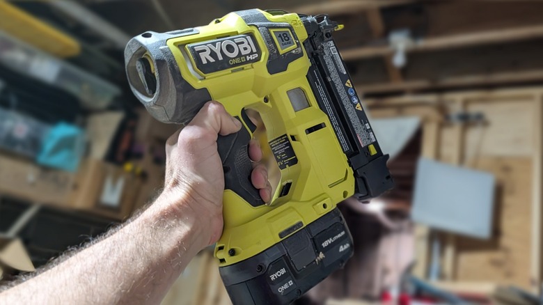 Ryobi nail gun held aloft in a workshop room.