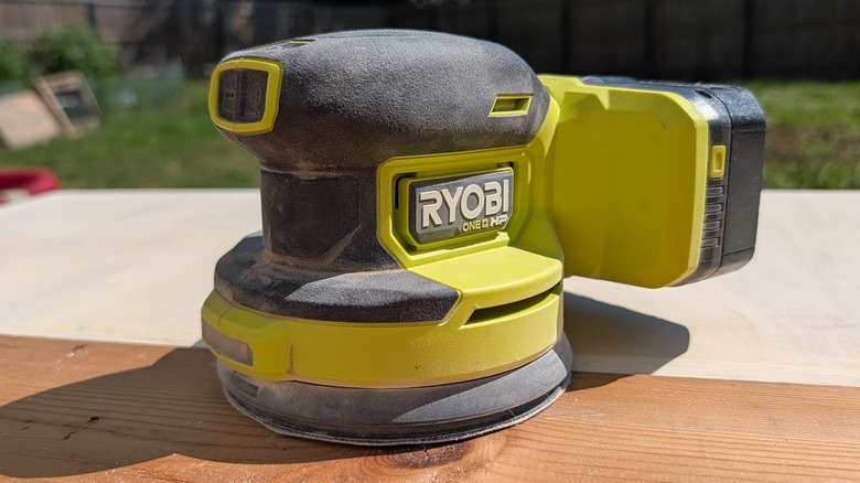 Ryobi orbital sander on a piece of wood in sunshine.