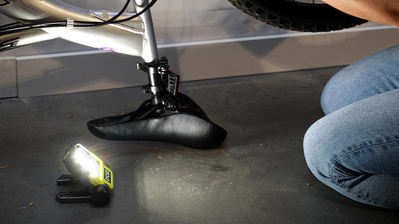 A Ryobi LED Flip Light on a floor lighting a bicycle