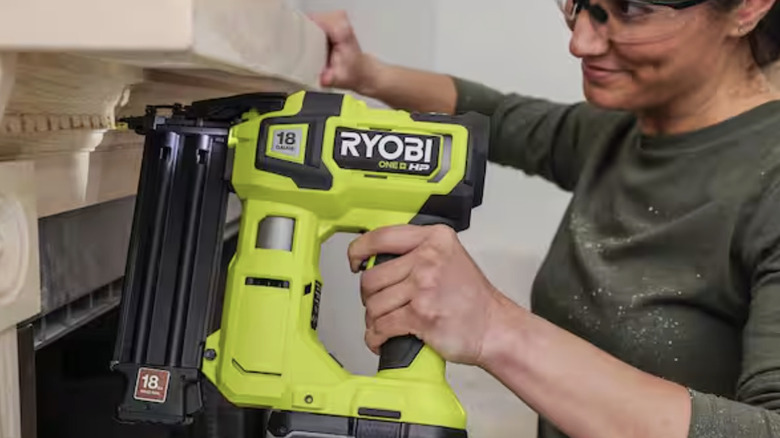 A smiling woman uses the Ryobi brushless brad nailer on a wood mantle
