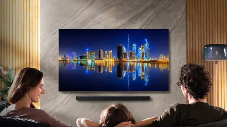 A family watching a wall-mounted Samsung smart TV.
