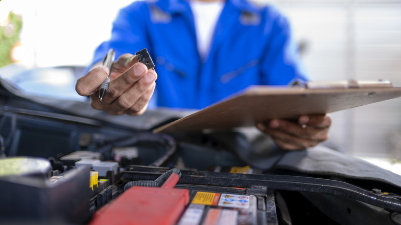 Close-up of mechanic inspecting car fuse.
