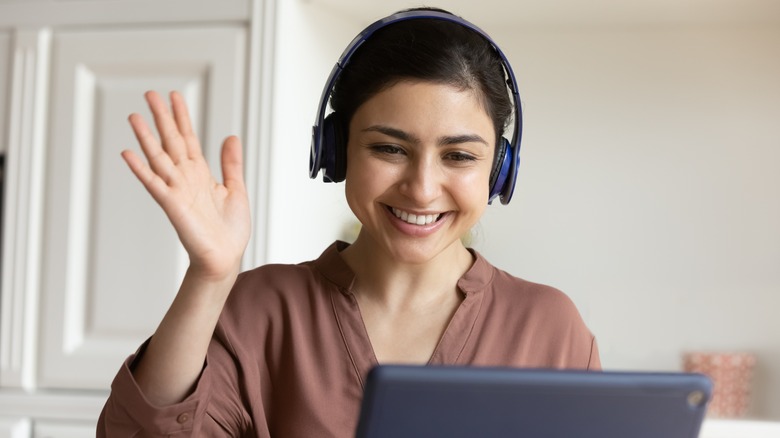 person smiling and waving at laptop screen