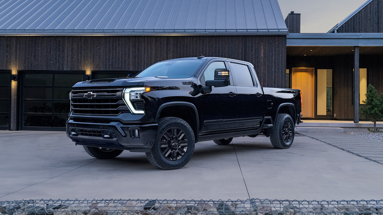 A black 2024 Chevrolet Silverado High Country parked in front of a house.