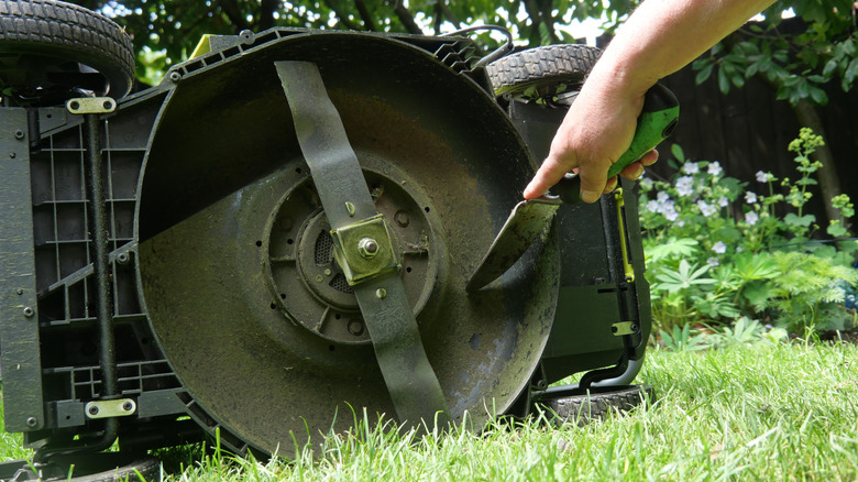 A person scraping out a lawn mower deck.