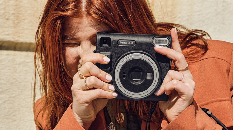 a woman using an Instax SQ40 camera aimed forward