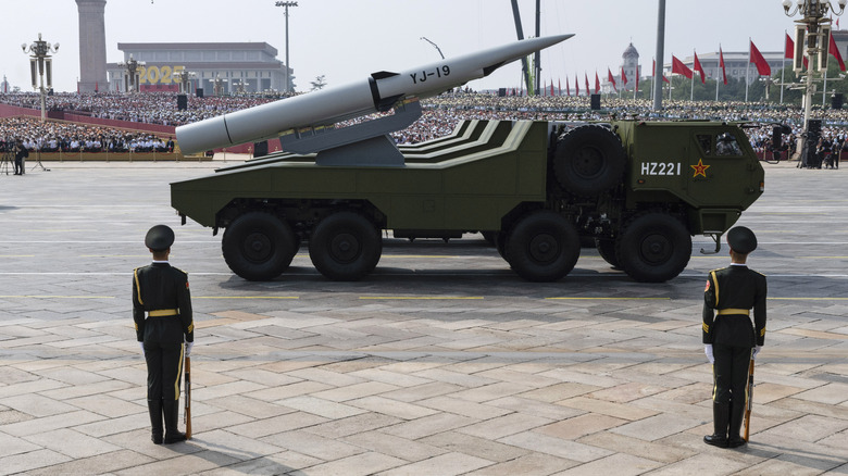 Chinese soldiers standing next to a mobile missile launch system