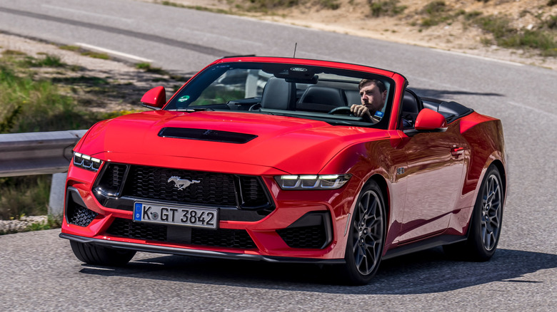 Ford Mustang GT convertible in red, front 3/4 view, mountain road, Cologne license plates