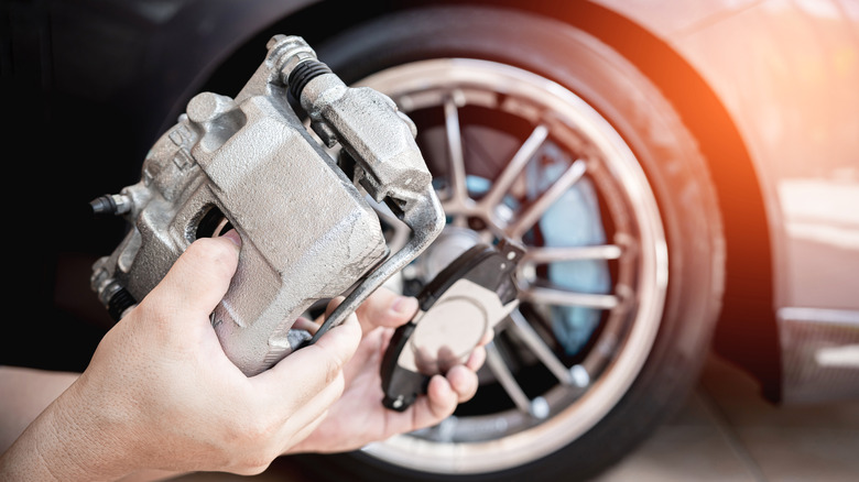 Person holding brake caliper and pads