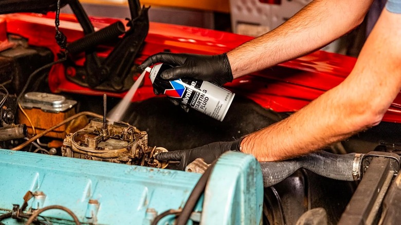 A mechanic using Valvoline starting fluid in a car.