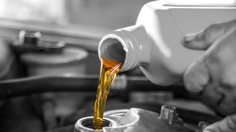 Pouring oil to car engine.