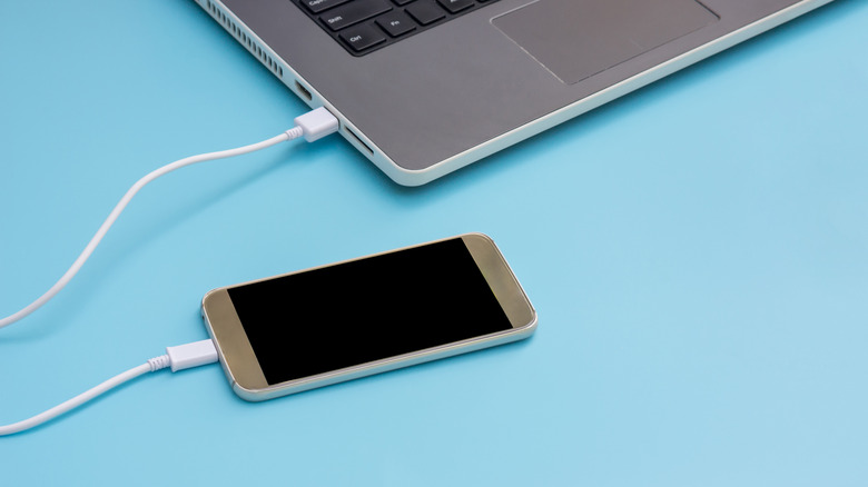 Smartphone connected to laptop sitting on blue table