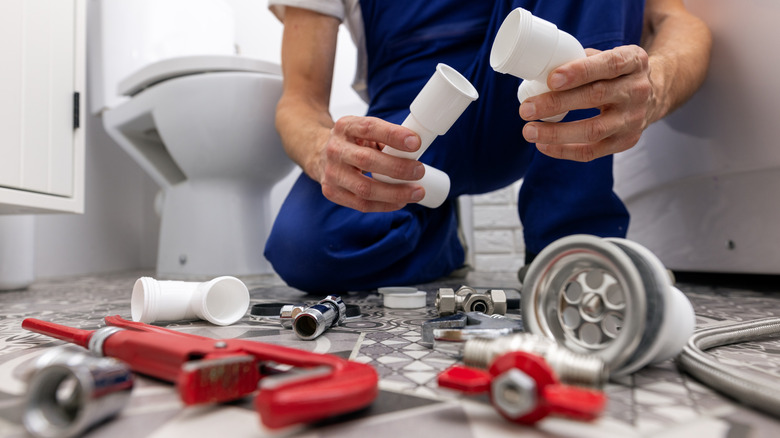 A plumber getting ready to install drain pipes in a bathroom