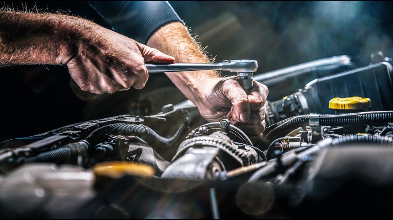 A mechanic with dirty hands working on a car.