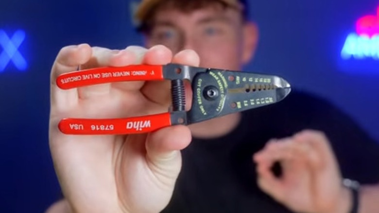 The American Electrician YouTube channel host holding a pair of Wiha wire strippers.