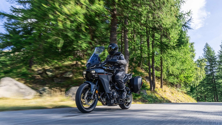 Person riding Yamaha touring motorcycle in wooded area.