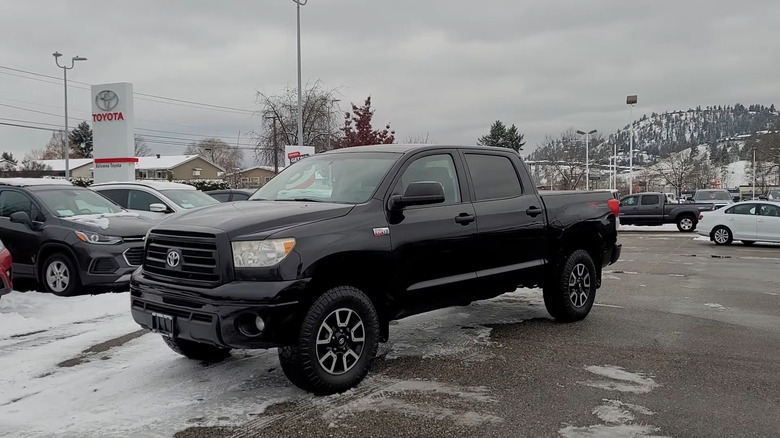 A black 2011 Toyota Tundra parked in a snowy Toyota dealership lot